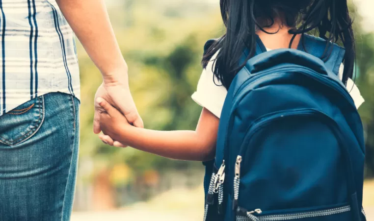 parent and child holding hands on their way to school