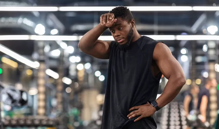 Exhausted sportsman cleaning sweat from his forehead