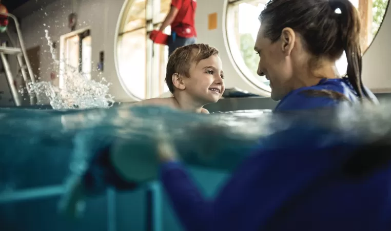 a happy child taking a swim lesson