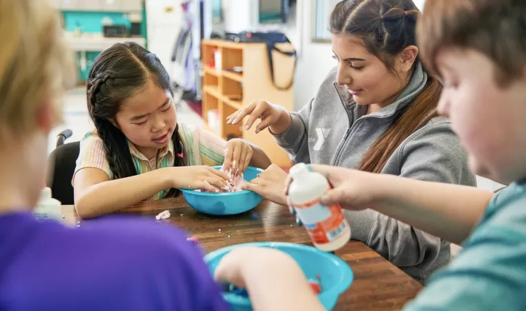 Child and YMCA staff member playing with slime