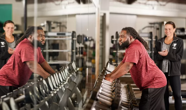 man grabbing dumbbells of a weight rack
