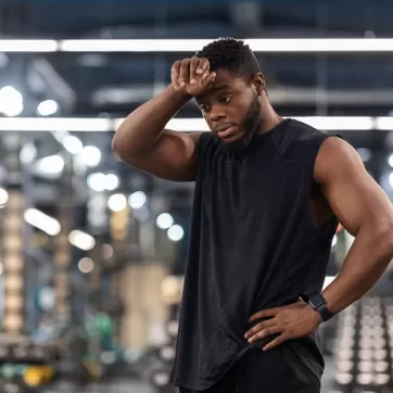 Exhausted sportsman cleaning sweat from his forehead
