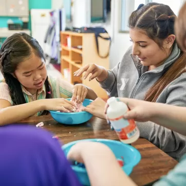 Child and YMCA staff member playing with slime
