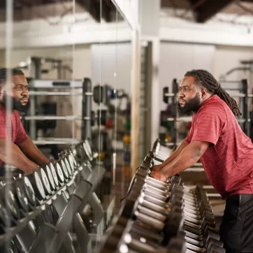 man grabbing dumbbells of a weight rack