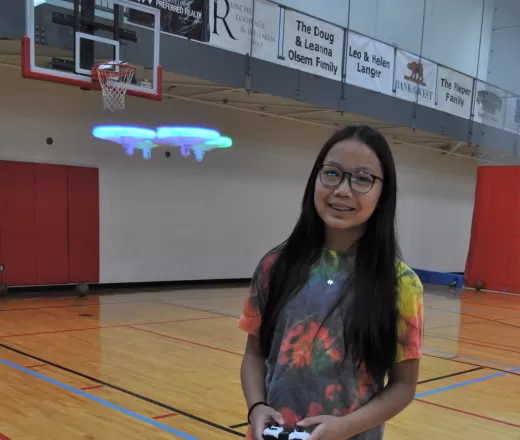 happy girl flying a remote control drone in a gymnasium